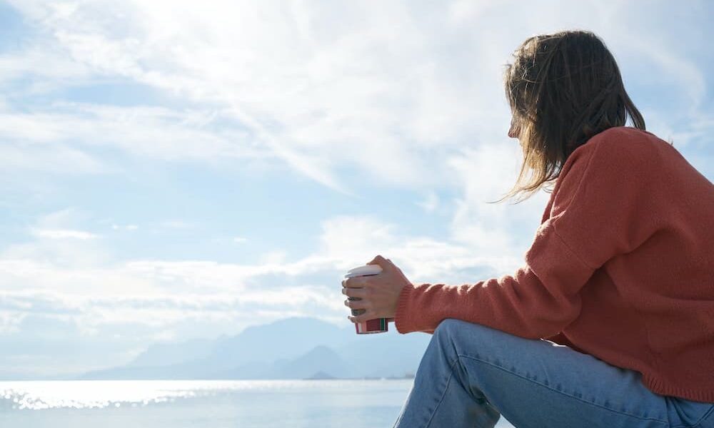 Person Sitting in Front of Body of Water